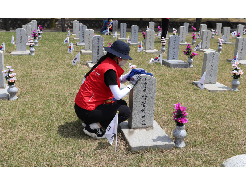 A woman is cleaning a gravestone.